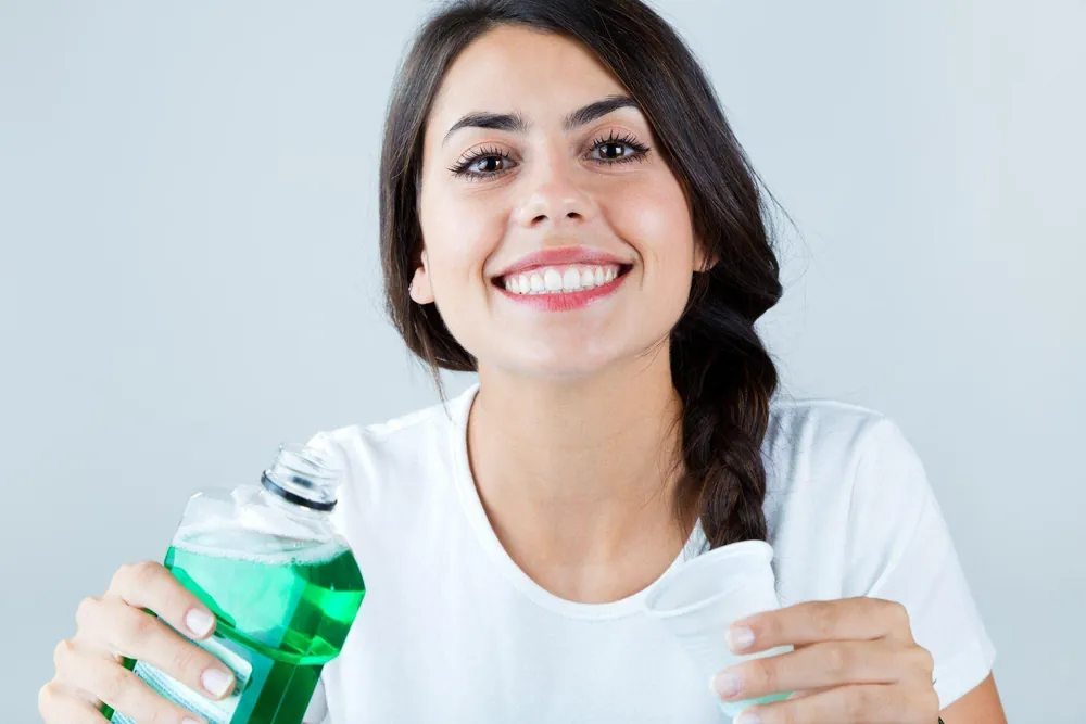is-mouthwash-bad-for-you Woman holding mouthwash and cup — is mouthwash bad for you? | Blodgett Dental Care